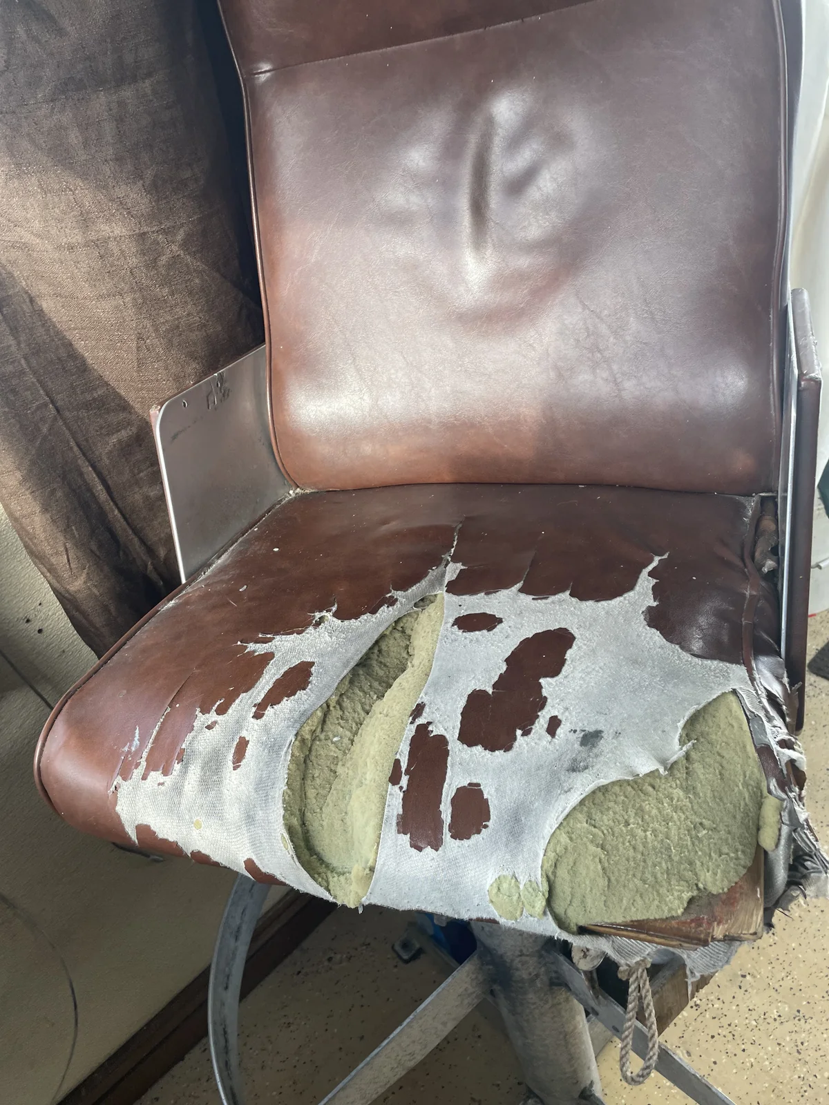 Before: marine chair with torn seat covering and exposed foam